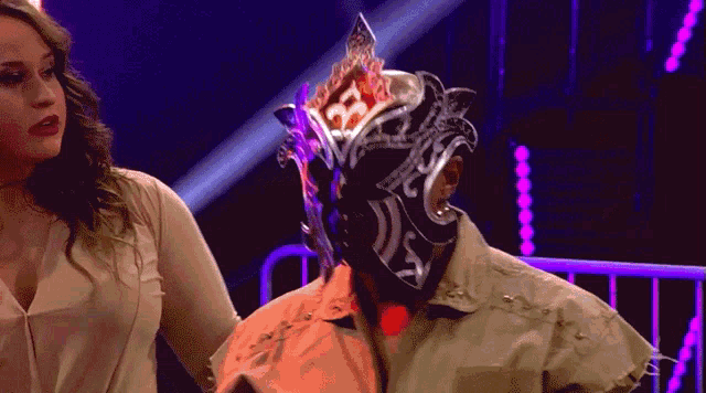 a woman stands next to a wrestler wearing a mask that says ' ss ' on it