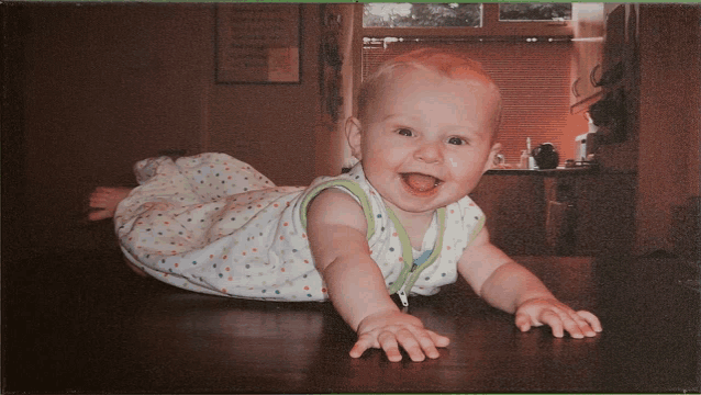 a baby in a polka dot sleeping bag is crawling on the floor