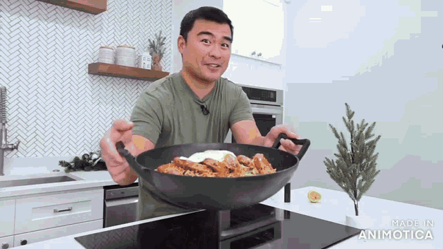 a man in a green shirt is holding a wok with food in it and the words made in animatica on the bottom right