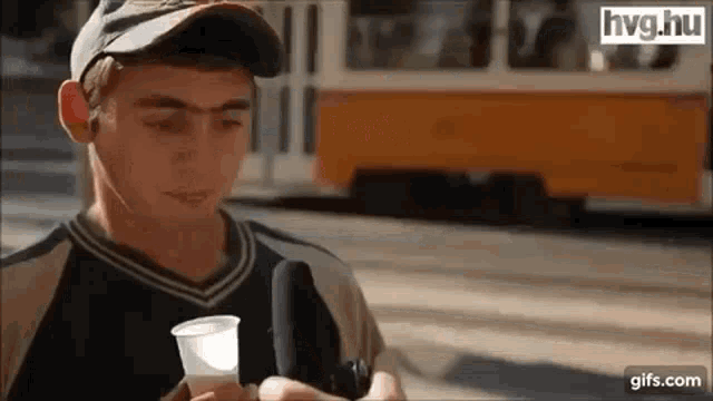 a young man is holding a cup and talking into a microphone in front of a trolley .