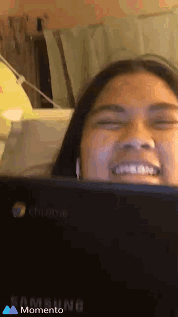 a woman smiles in front of a samsung laptop