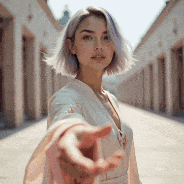 a woman in a white dress reaches out her hand towards the camera
