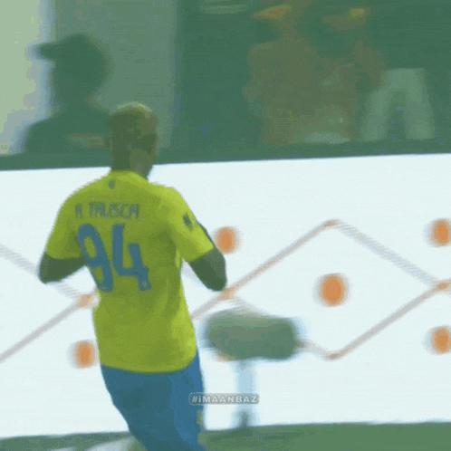 a man wearing a yellow jersey with the number 94 on the back