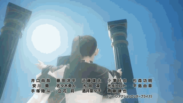 a woman stands in front of two columns with the sun shining through them