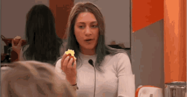 a woman with blue hair is holding a piece of food in her hand