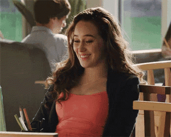a woman in a pink top is smiling while sitting at a table