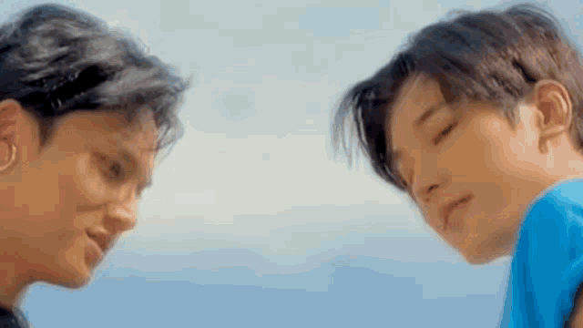 two young men are standing next to each other with their eyes closed .