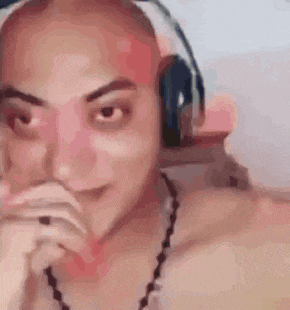 a bald man wearing headphones and a necklace is smiling .