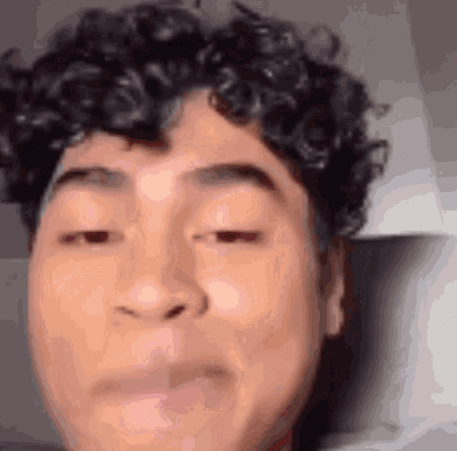 a close up of a young man 's face with curly hair .
