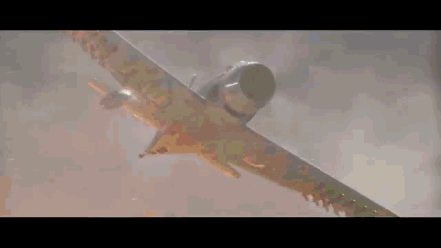 a plane is flying over a field of fire and smoke
