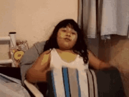 a young girl is sitting in a chair with a striped blanket on her chest .