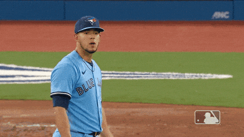 a man wearing a blue jays jersey is raising his arms in the air