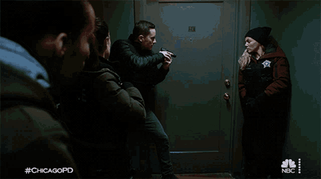 a man holding a gun in front of a door that says #chicagopd on it