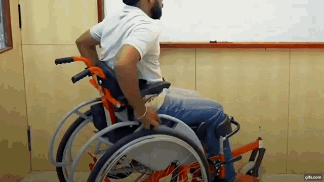 a man is sitting in a wheelchair in front of a white board