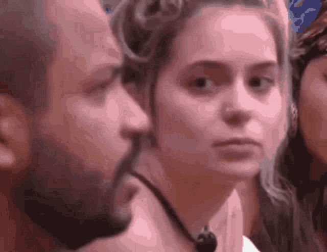 a man and a woman are standing next to each other in a crowd and the woman is looking at the man .