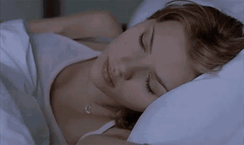 a woman is laying in bed with a pillow on her head .