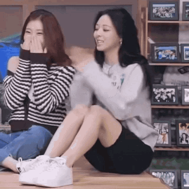 two women are sitting next to each other on the floor .
