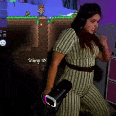 a woman in a striped jumpsuit is playing a video game while holding a remote control .