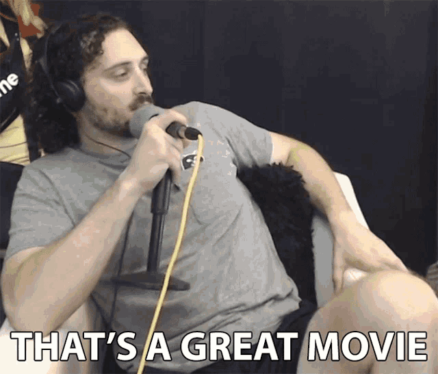 a man sitting in front of a microphone with the words that 's a great movie below him