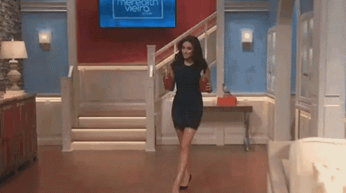 a woman in a black dress is walking down stairs while holding a cup .