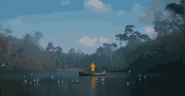 a man in a yellow jacket is fishing in a small boat