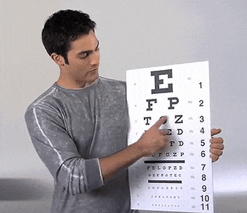 a man is pointing at an eye chart with the letter e