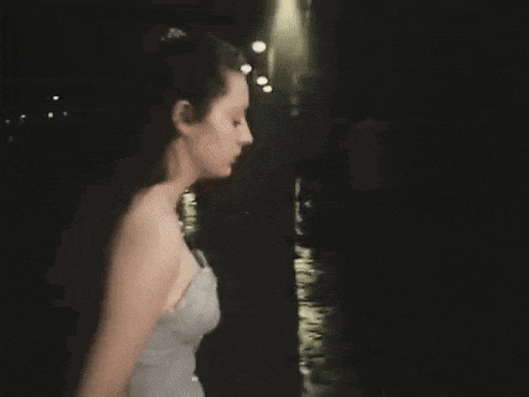 a woman in a dress is walking down a street at night .