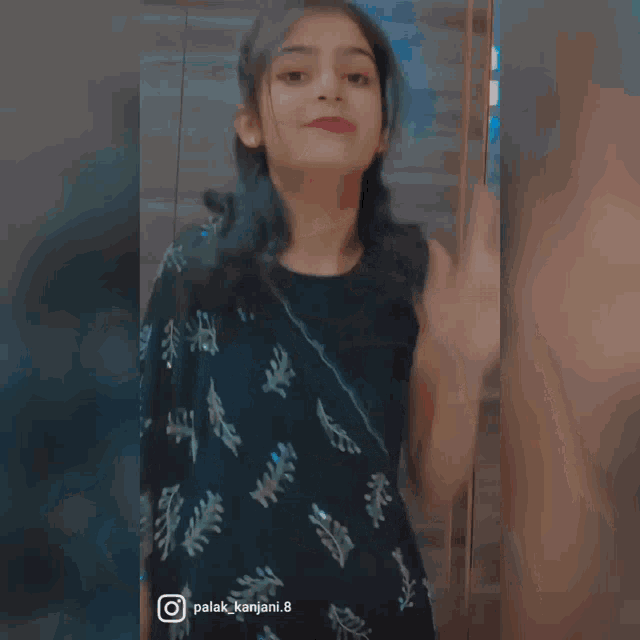 a girl in a black dress is standing in front of a mirror with the name palak_kanjani.8 on the bottom right