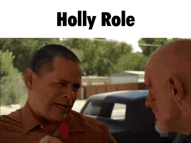 two bald men are talking in front of a sign that says holly role on it