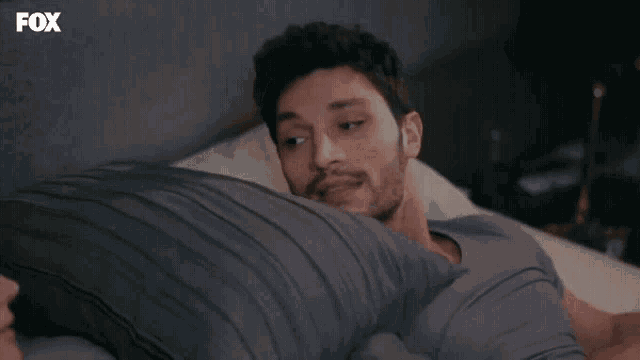 a man is laying on a bed with a fox logo in the corner