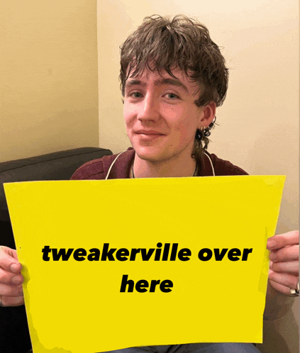 a young man holds a yellow sign that says tweakerville over here