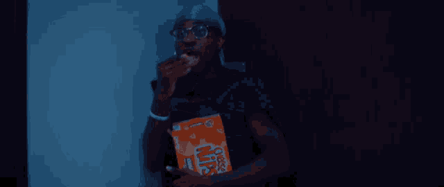 a man wearing glasses and a headband is holding a bag of ritz crackers .