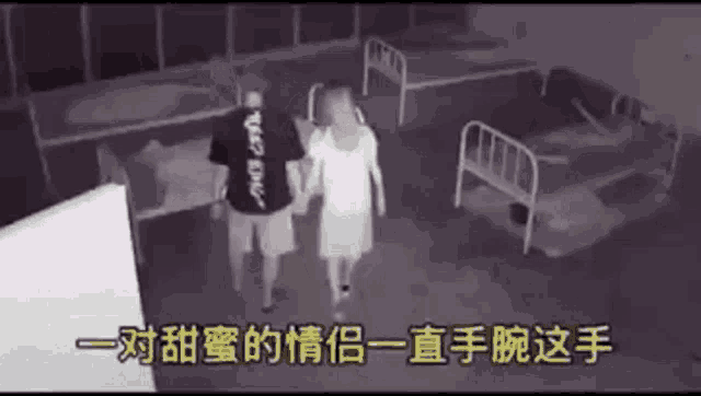 a man and a woman are holding hands in a dark room with a lot of beds .