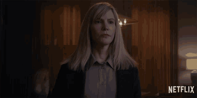 a woman in a suit holds her hand up in front of a netflix logo