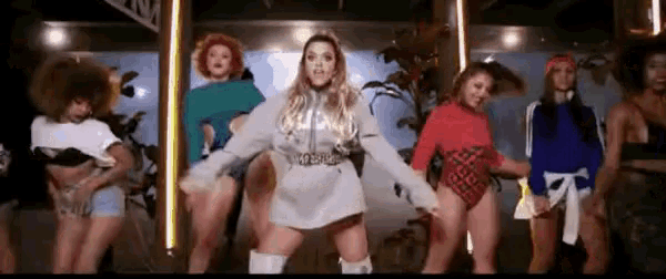 a group of women are standing next to each other dancing in a room .