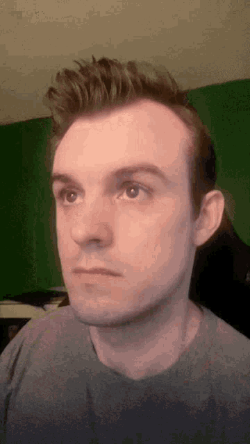 a man 's face is shown in front of a green wall