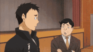 a man in a suit and tie is talking to another man in a jacket .