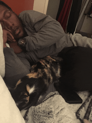 a man with a watch on his wrist sleeping next to a cat