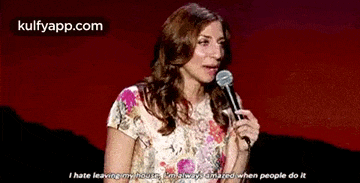 a woman is holding a microphone on a stage and saying `` i hate leaving my house .