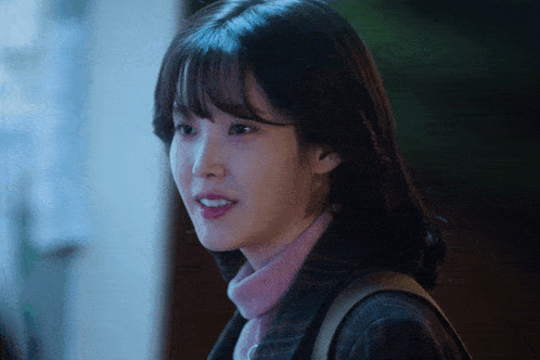 a close up of a woman 's face with a pink sweater