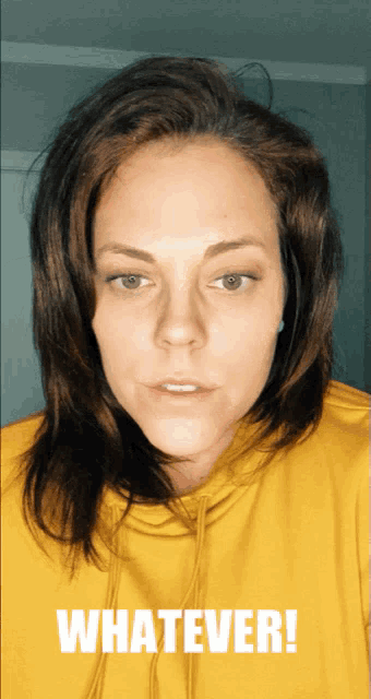 a woman wearing a yellow hoodie with the word whatever written on it