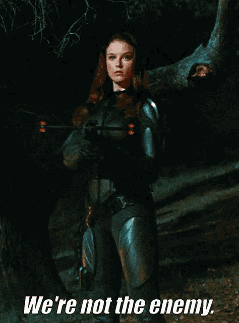 a woman holding a bow and arrow with the words we 're not the enemy
