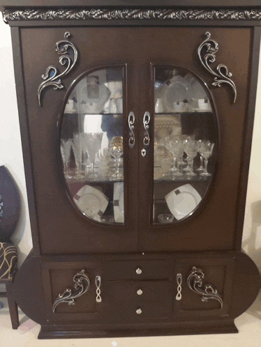 a cabinet with a glass door has a reflection of a person in the glass door