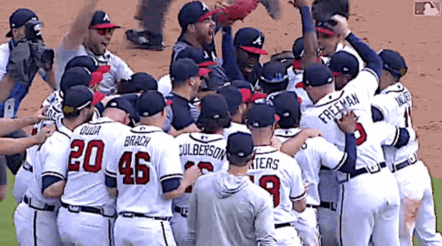 a group of baseball players are huddled together and one of them has the number 20 on his jersey