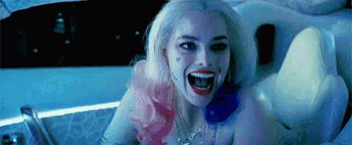 a woman in a suicide squad costume is sitting in a tub with her mouth open .