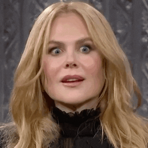 a close up of a woman 's face with blonde hair and blue eyes making a funny face .
