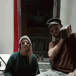 a man and a woman wearing sunglasses and hats are sitting next to each other
