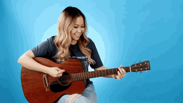 a woman playing an acoustic guitar with a t-shirt that says " and sounds like you "