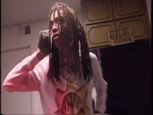a man with dreadlocks is wearing a pink shirt