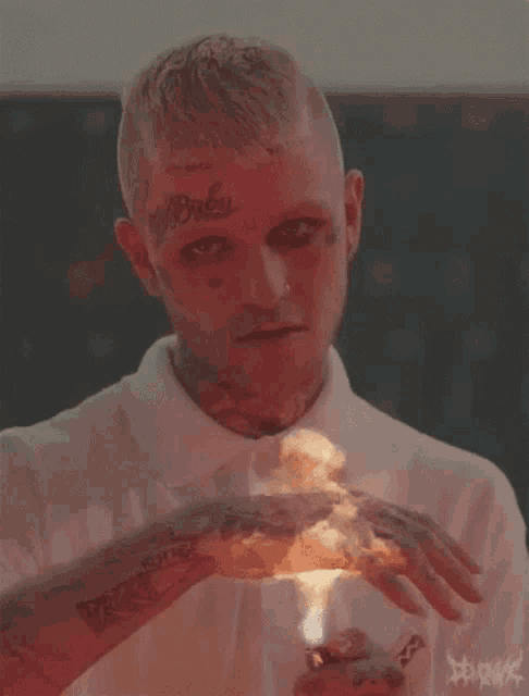 a man with a tattoo on his face is holding a lighter in his hands .